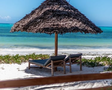 a beach umbrella with two sun bed at Villa Serene Zanzibar 