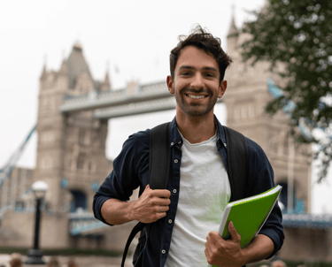 İngiltere'de Londra Köprüsünün önünde bir öğrenci değişim programı öğrencisi gülümsüyor