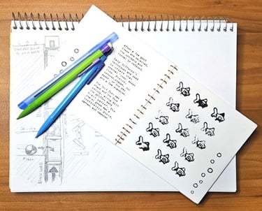 Pencils and pens on a handmade brand identity book which sits on top of an idea sketch pad