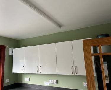 a kitchen with a green wall and white cabinets