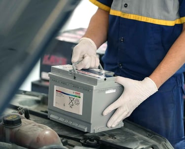 فني يقوم بتركيب بطارية سيارة جديدة في الكويت