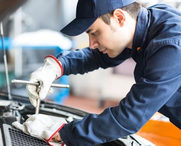 فني يقوم بتركيب بطارية سيارة جديدة في الكويت