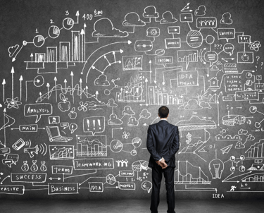 a man in a suit standing in front of a chalkboard with a drawing of