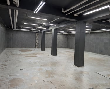 Large basement studio with a concrete floor and grey walls