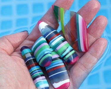 a hand holding a selection of surfite or surf stone cabochons in bright colours