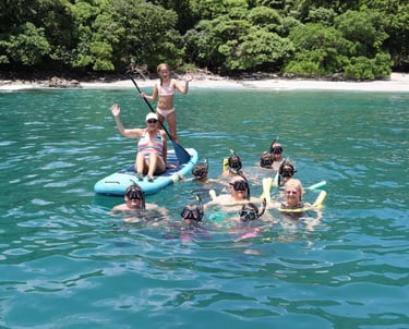 Family enjoying snorkeling and paddle boards in turquoise waters during catamaran tour Papagayo