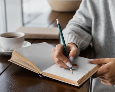 a person holding a pencil and writing on a notebook