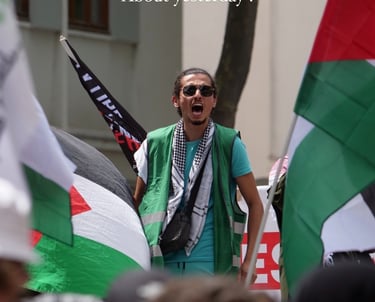 a man in a green vest and sunglasses with a flag