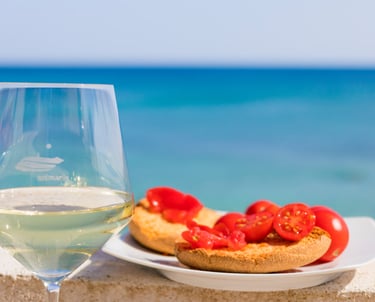 a glass of wine and bread with tomatoes on a table