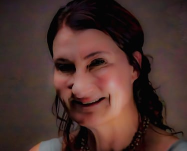 A smiling woman with dark hair and a beaded necklace in a professional headshot portrait.