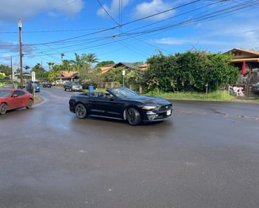 a car driving down a street with cars parked on the side of the road