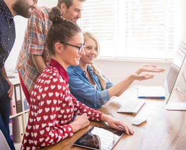 Groupe de personnes souriantes travaillant ensemble sur un ordinateur.