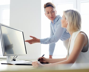 Un professionnel en chemise bleue montre des informations sur un écran d'ordinateur à une femme blo