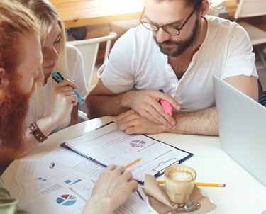 Trois personnes assises à une table, concentrées sur un document pendant une session de formation.