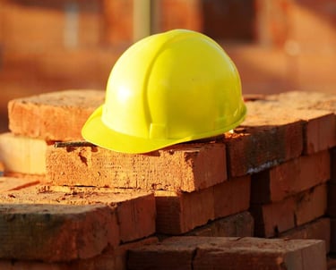 a yellow hard hat with a yellow hard hat on top of a pile of bricks