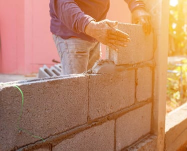 a man is building a brick wall with a cement block wall