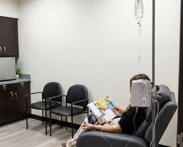 Patient receiving IV infusion therapy while seated in a comfortable recliner in a neurology clinic.