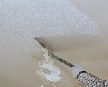 Scraper removing popcorn ceiling texture