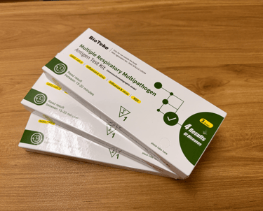 BioTeke multiple respiratory multipathogen antigen test kits for COVID-19, Influenza, and RSV on a desk.
