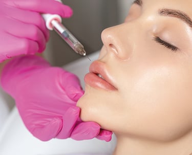 a woman getting her lips painted pink by a professional makeup artist