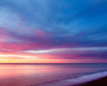 a sunset on a beach with a lighthouse in the background