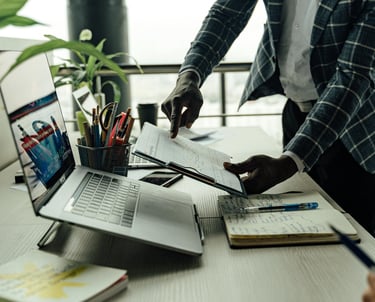 a man in a suit and tie is standing at a desk with a laptop