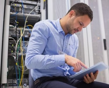 a man in a blue shirt is holding a tablet computer and looking at a tablet