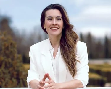 Rebeca Rueda Gallego, formadora y facilitadora experta en comunicación no verbal, sonriendo al aire libre con un blazer blanc