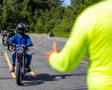 Mokinys vairuoja motociklą instruktoriaus prieziūroje aikštelėje