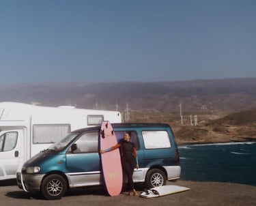 a man standing next to a van with a surfboard