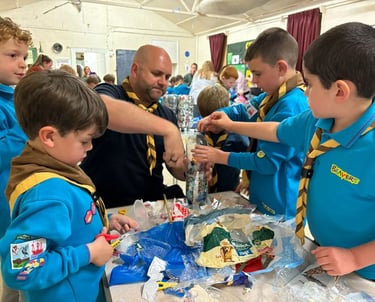 Beaver Scouts working with a leader to fill plastic bottles with eco-bricks made of plastic waste.