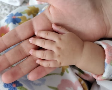 A mom's hands holding a baby's hand