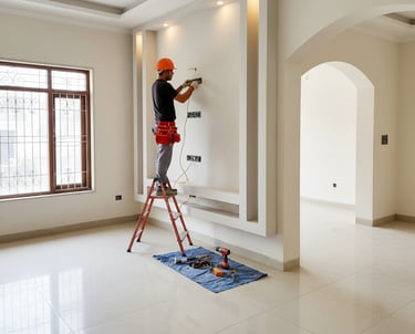 Professional electrician on a ladder installing wiring for a modern home entertainment wall.
