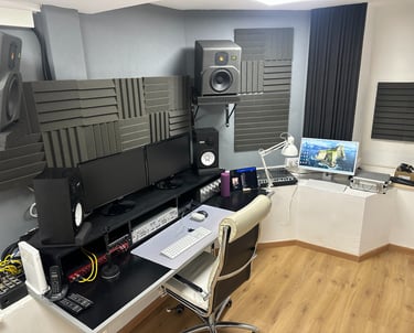 a recording studio with a computer monitor, speakers, and a laptop