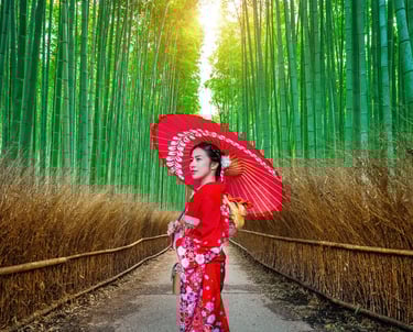 A woman in a red Japanese kimono holding a red umbrella in the Arashiyama Bamboo Grove in Kyoto.