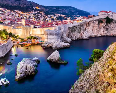 Night view of Dubrovnik Old Town walls and West Harbour with illuminated coastal fortifications in Croatia.