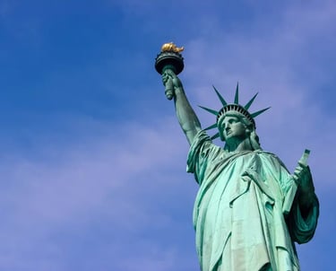 The Statue of Liberty holding her torch against a clear blue sky in New York City.