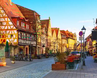 Charming cobblestone street in Nuremberg, Germany, featuring traditional half-timbered houses and outdoor cafes.