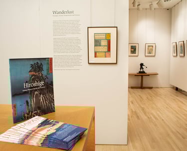 exhibition installation photo including catalog, wall text, and prints