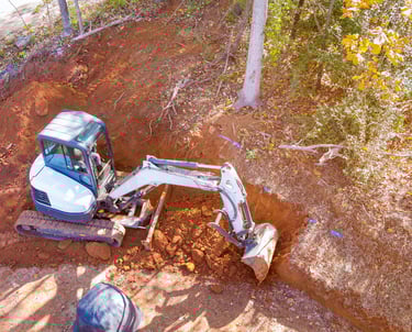 mini-excavator-digging-out-hillside.png