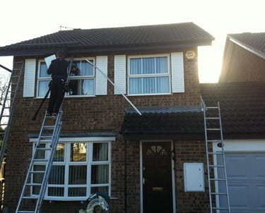 a man on a ladder ladder to reach up to a house