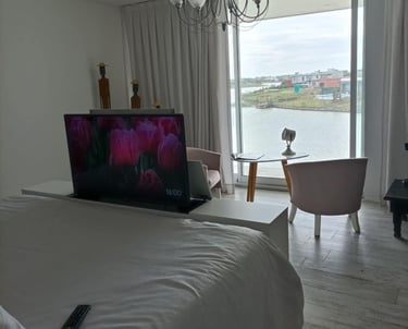 Mueble pie de cama con elevador de TV motorizado frente a ventanal en dormitorio moderno