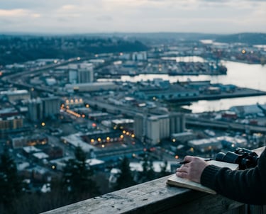 A person standing on an overlook looking down on a city waking up to the morning.