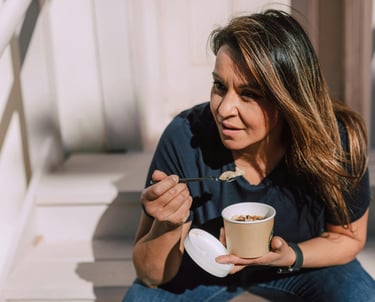 she is eating healthy snack with spoon at the office stairs during lunch while relaxing