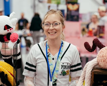 A very happy vendor stands with the crochet art she is selling.