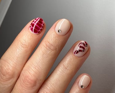 Image of perfectly manicured hands with red nails with patterns in them