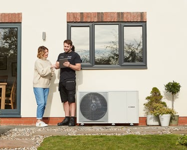 a man and woman in front of a outside heat pump
