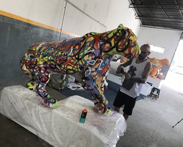 érgio Astral posando ao lado de sua criação, uma escultura de onça-pintada estilizada