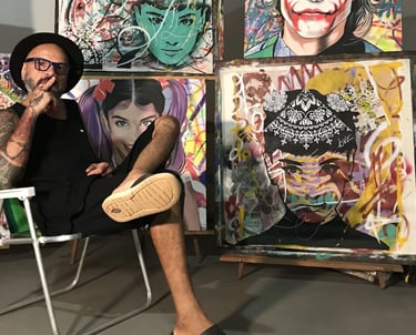 Sérgio Astral em seu estúdio, rodeado por suas obras de arte e materiais de pintura.