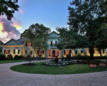 a large house with a fountain in the middle of the yard